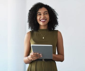 Une femme professionnelle souriant et tenant sa tablette en mains