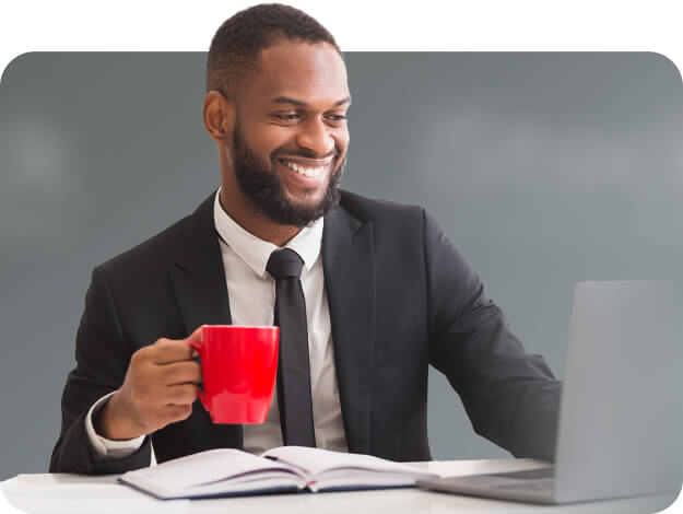 Jeune homme professionnel travaillant son son ordinateur portable, une tasse rouge en main