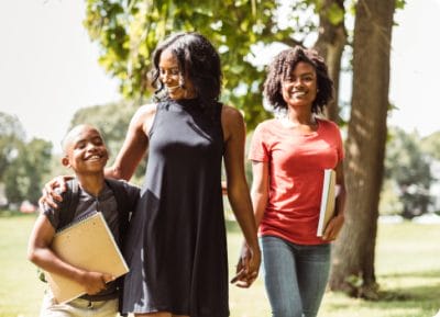 Une famille de trois composée d'une mère, avec à sa droite sa fille qui est une jeune adolescente et à sa gauche son fils qui est plus jeune et portant à son dos son sac d'école