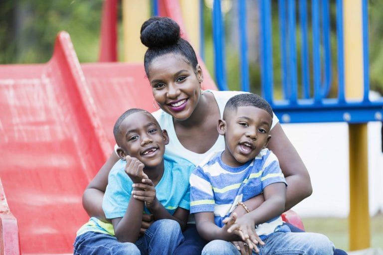 Famille de trois, une mère et ses deux garçons. Ils sourissent tous, fixant la caméra du regard