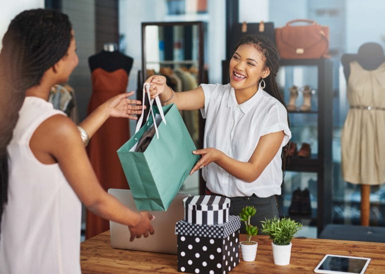 Vendeuse dans un magasin de vêtements, remettant un paquet à une cliente