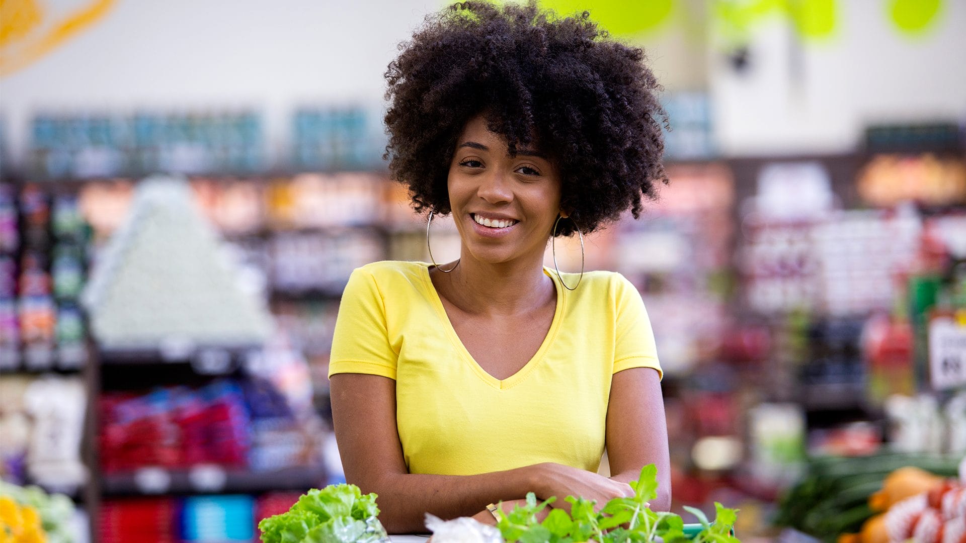 Femme souriant et fixant la caméra du regard pendant qu'elle fait ses courses au supermarché