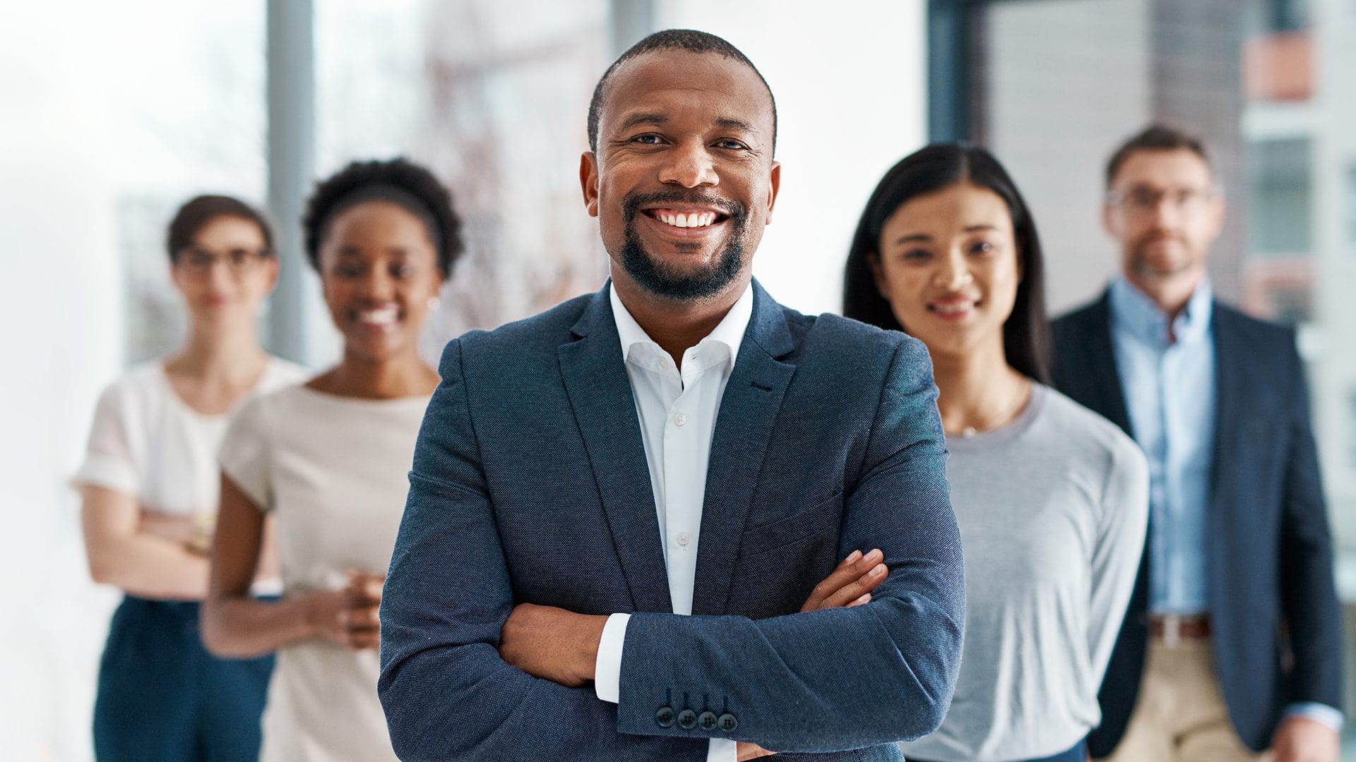 Groupe de professionnels confiants et souriants, fixant la caméra de regard