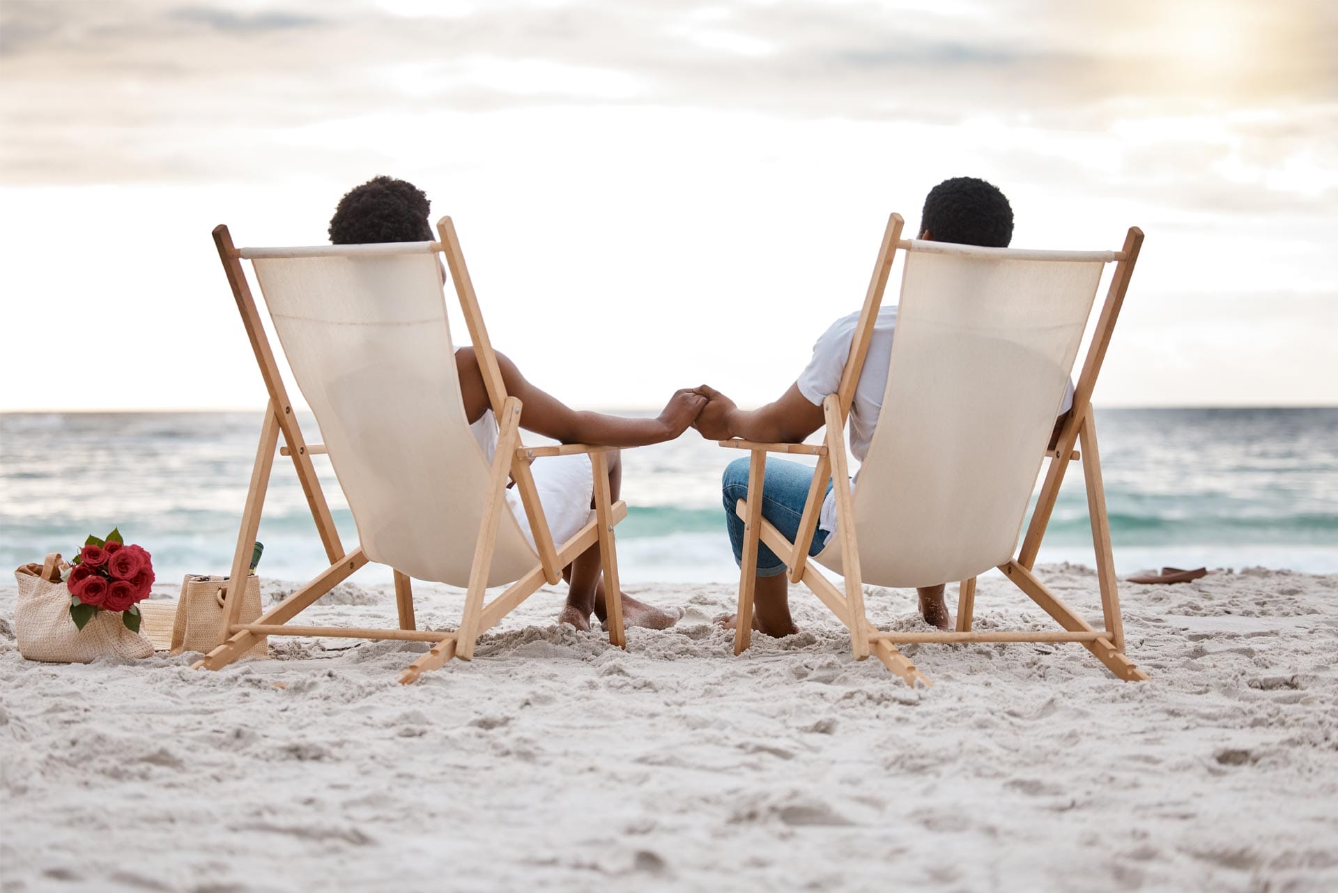 Couple assis sur des chises, les pieds au sable, regardant la plage