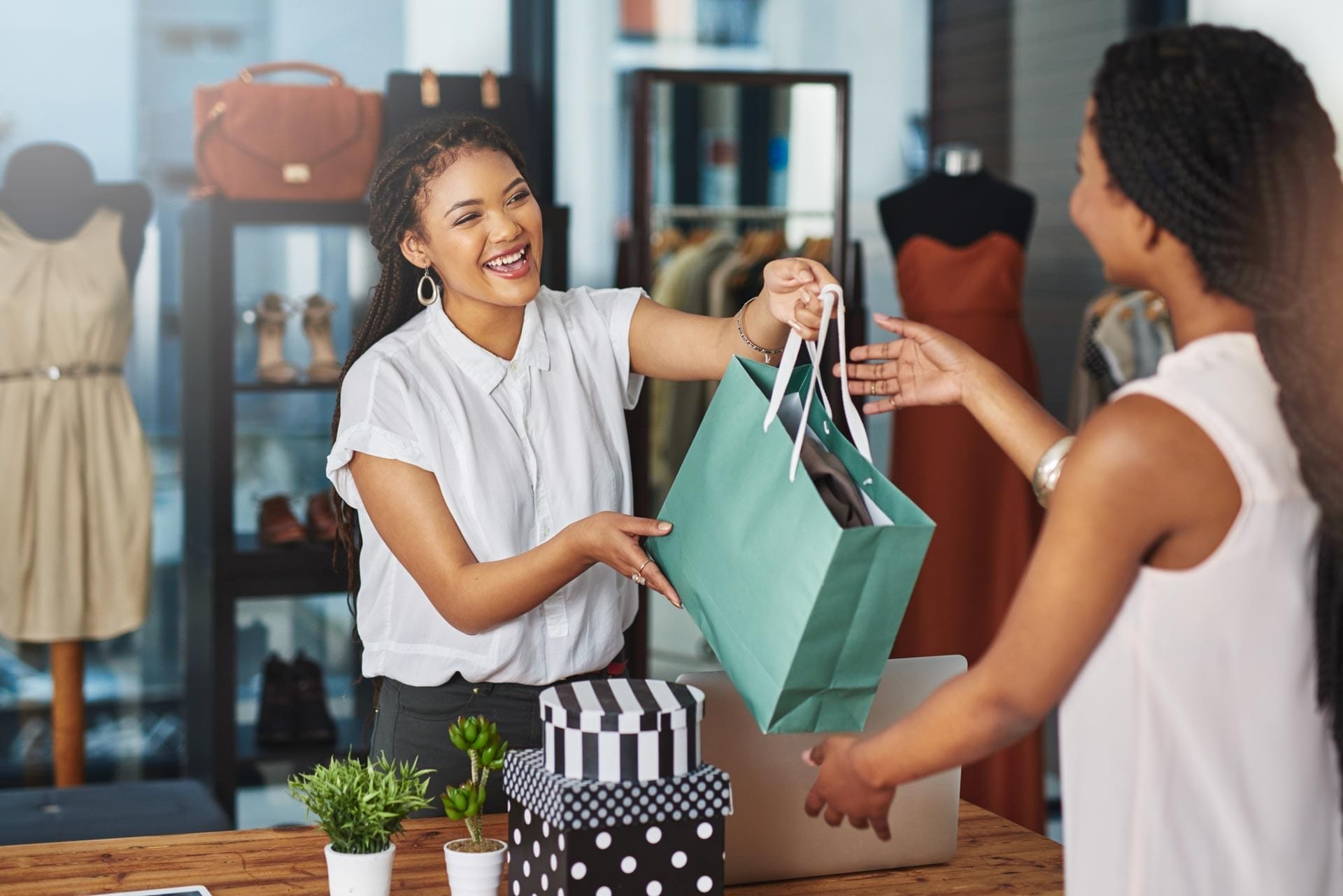 Vendeuse remettant à une cliente un sac d'achat dans un magasin de vêtements