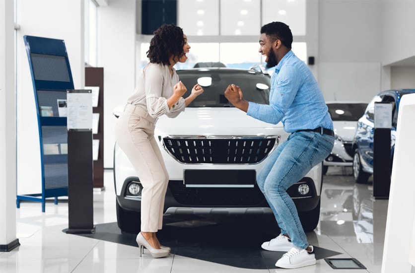 Couple, dans un showroom de véhicules, heureux car il vont acheter une voiture