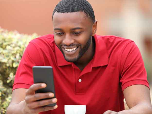 Jeune homme heureux, détendu, tenant son téléphone, utilisant avec joie les services bancaires en ligne de Capital Bank, Capital Bank Online