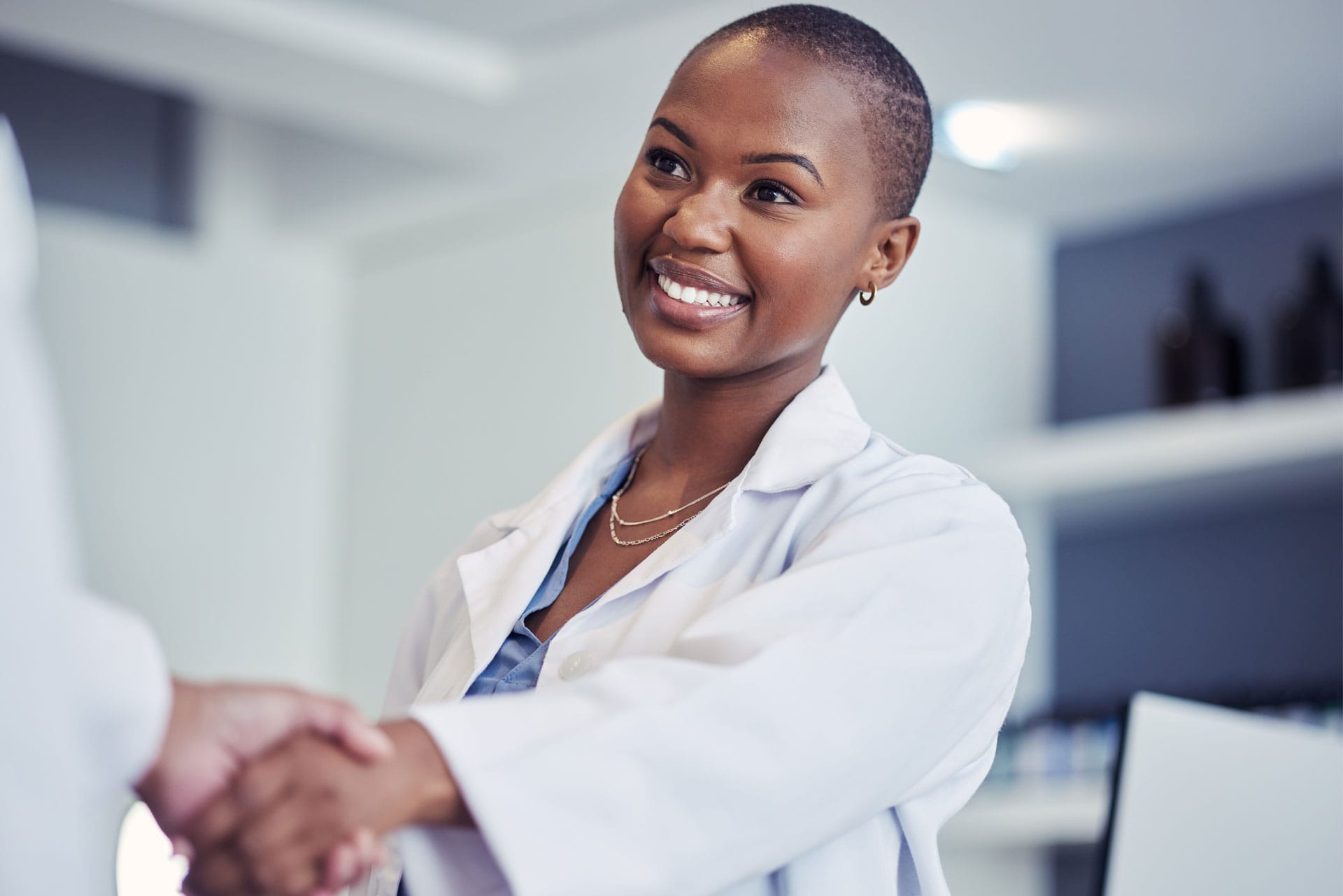 Femme confiante et souriante, tendant la main à une autre personne qu'elle regarde dans les yeux