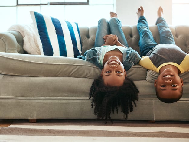 Deux enfants heureux couchés, tête en bas, sur un divan