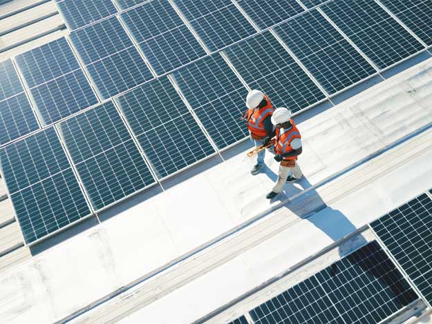 Image de deux techniciens marchant sur une plateforme de panneaux solaires, illustrant le Crédit Énergie