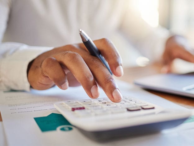 Professionnel travaillant sur son ordinateur portable en faisant des calculs sur une calculatrice