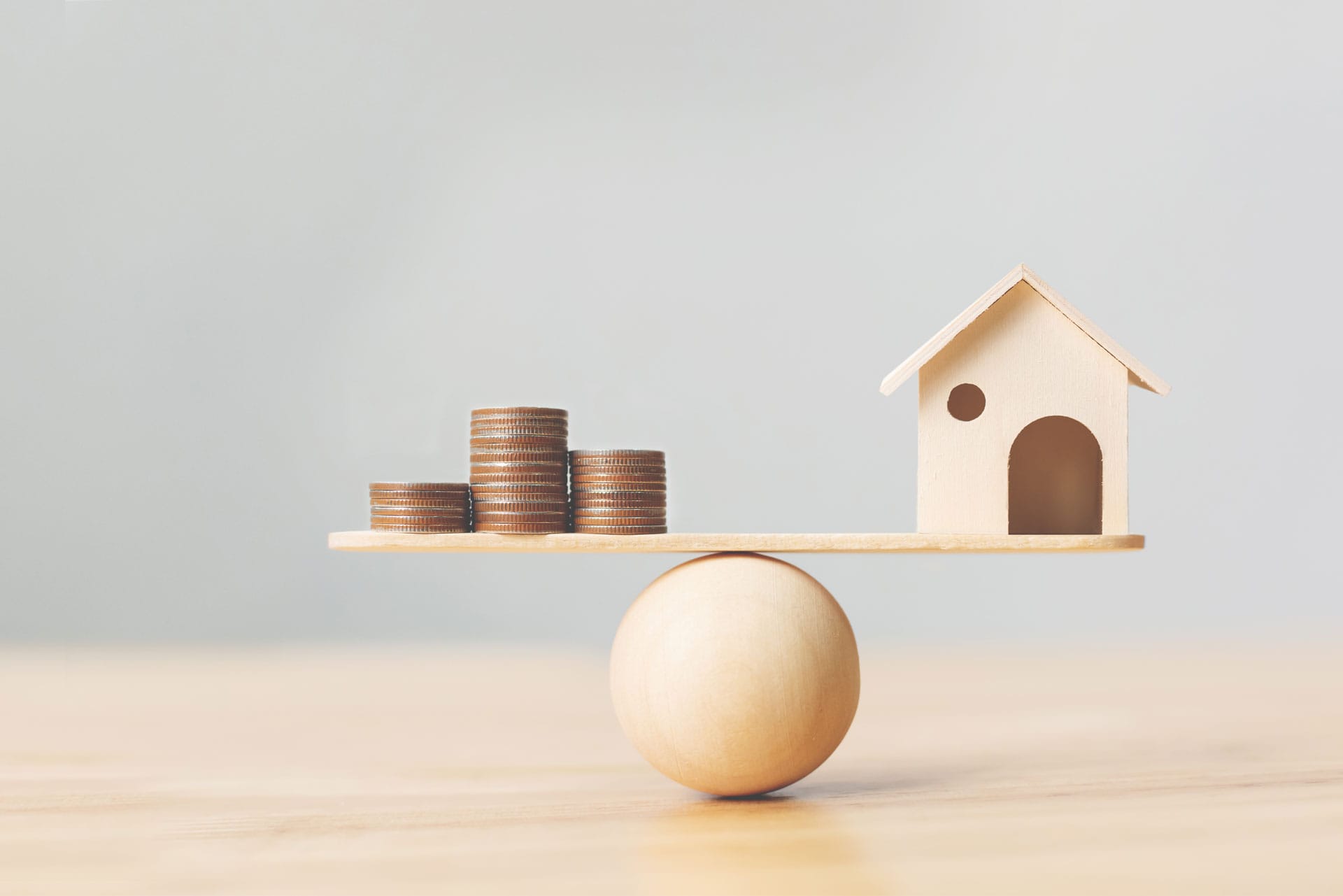 Photo illustrant une balance avec d'une part une maison et d'autre part de l'argent, symbolisant visuellement le concept du Home Equity Loan