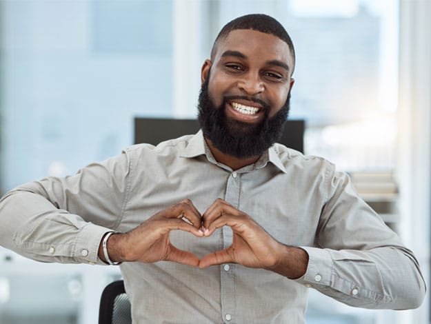 Employé homme heureux faisant un cœur avec ses deux mains